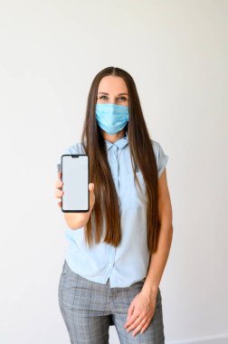 Woman in medical mask demonstrates a phone screen clipart