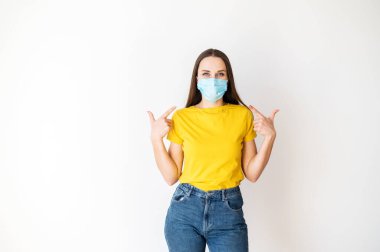 Kadın yüzündeki tıbbi maskeyi işaret ediyor.