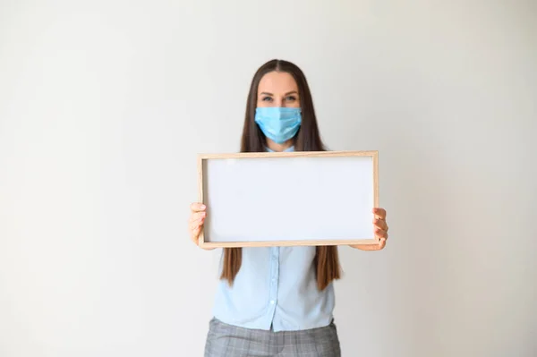 Frau mit medizinischer Maske steht mit leerem Brett — Stockfoto