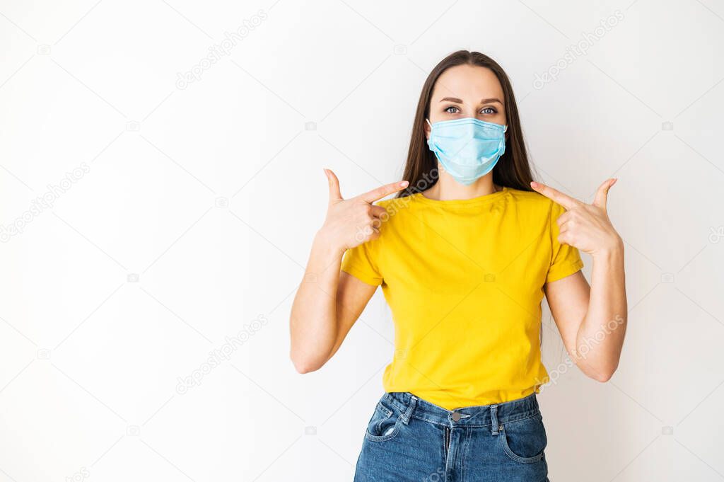 Woman points to medical mask on her face