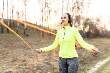 Dışarıda ip atlayan zinde bir kadın.