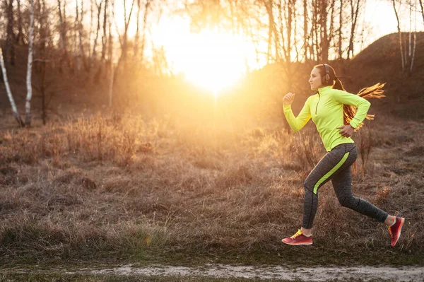 Young woman in sports wear with earphones jogging