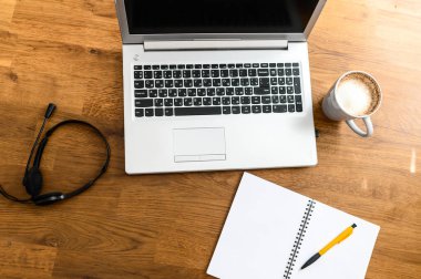 Dizüstü bilgisayar, elsiz kulaklık ve düz kahve.