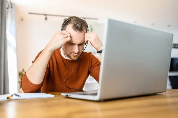 El tipo usa auriculares manos libres para trabajar desde casa. — Foto de Stock