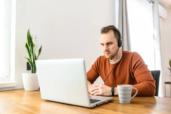 Le gars utilise des écouteurs mains libres pour travailler de la maison — Photo