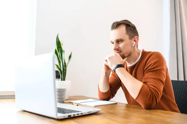 Kerl schaut auf Laptop und Notizen im Notizbuch — Stockfoto