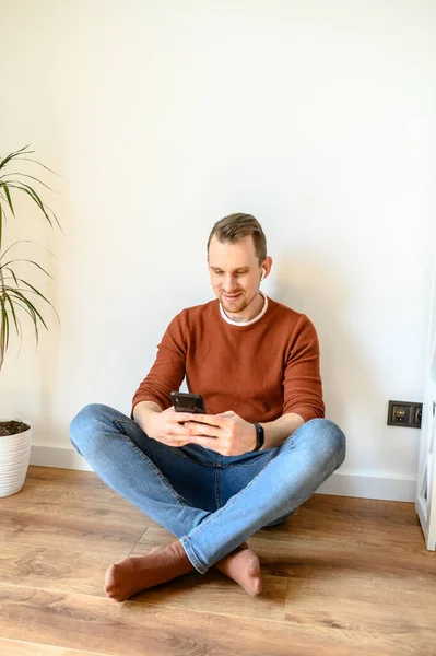 Jongeman chatten aan de telefoon thuis — Stockfoto