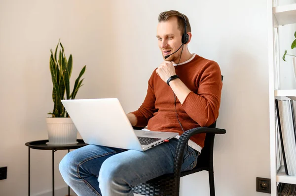 Guy gebruikt headsets en laptops om thuis te werken — Stockfoto