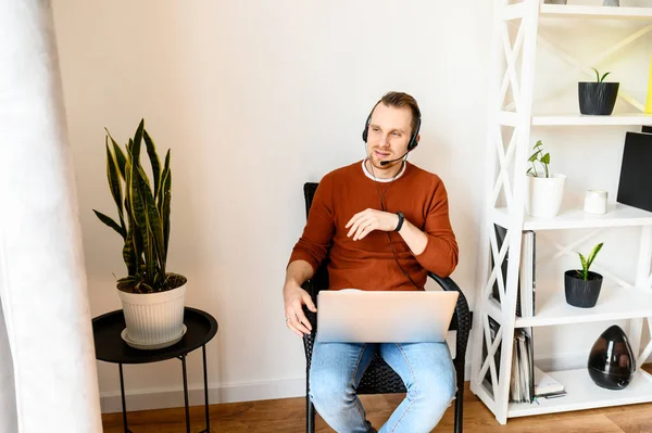 Guy gebruikt headsets en laptops om thuis te werken — Stockfoto
