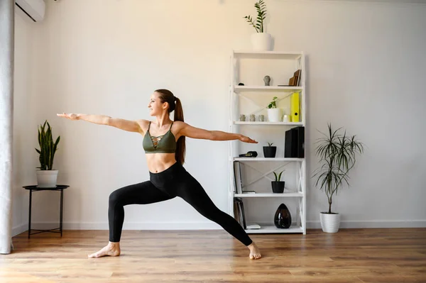 Junge positive Frau praktiziert Yoga zu Hause — Stockfoto