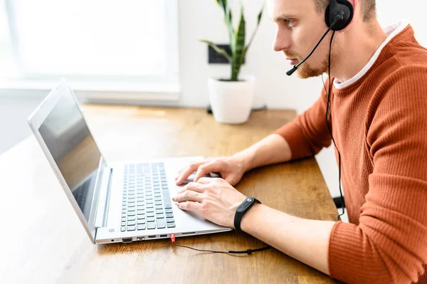 El tipo usa auriculares manos libres para trabajar desde casa. —  Fotos de Stock