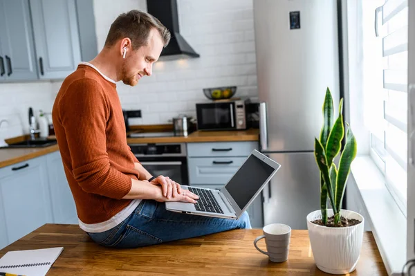 Bureau à domicile. Un gars utilise un ordinateur portable à la cuisine — Photo