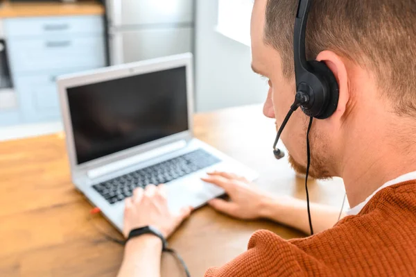 El tipo usa auriculares manos libres para trabajar desde casa. —  Fotos de Stock