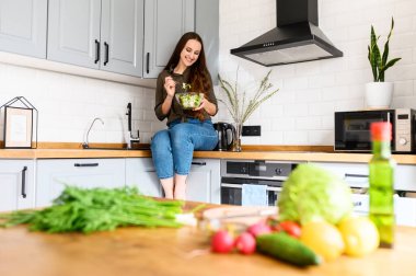 Bir kadın kaseden taze salata yiyor.