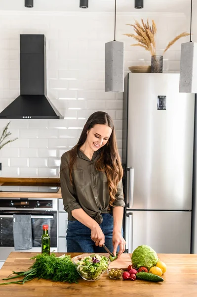 Una giovane donna felice che prepara un'insalata a casa — Foto Stock