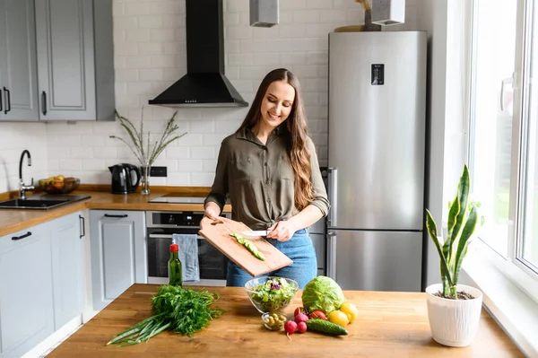 Menina cortou pepino fresco e joga-lo para salada — Fotografia de Stock