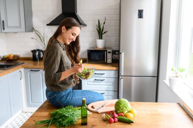Bir kadın kaseden taze salata yiyor.
