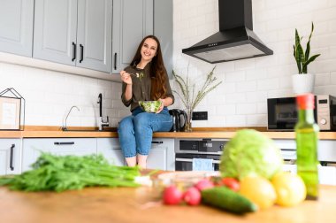 Bir kadın kaseden taze salata yiyor.