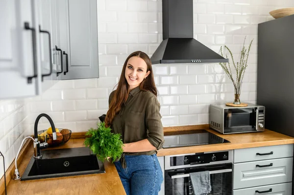 Una donna con un mucchio di aneto in mano in cucina — Foto Stock