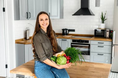 Elinde bir sepet taze sebze tutan genç bir kadın.