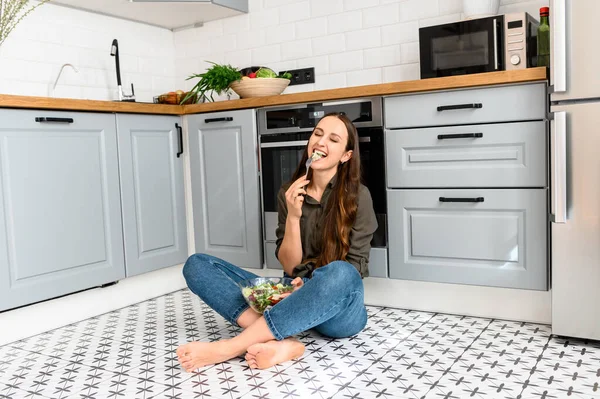 Una donna sta mangiando un'insalata fresca da una ciotola — Foto Stock