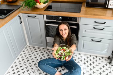 Elinde taze salata olan bir kadın.