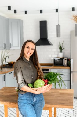 Elinde bir sepet taze sebze tutan genç bir kadın.