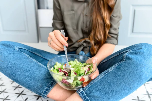 Une femme mange une salade fraîche dans un bol — Photo