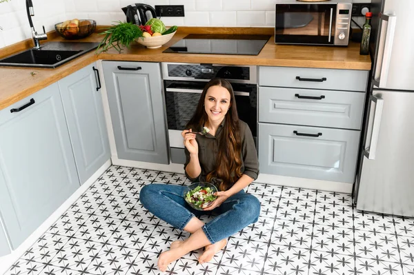 Una donna sta mangiando un'insalata fresca da una ciotola — Foto Stock