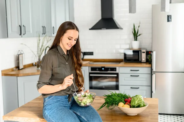 Mulher comer comida saudável na cozinha acolhedora — Fotografia de Stock