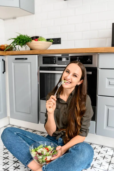 Una donna sta mangiando un'insalata fresca da una ciotola — Foto Stock