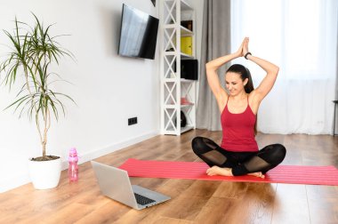 Genç bir kadın evde yoga yapıyor.