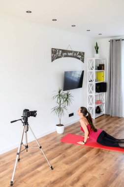 Genç bir kadın yoga videolarını evde kaydediyor.