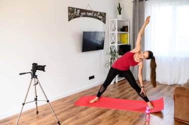Genç bir kadın yoga videolarını evde kaydediyor.