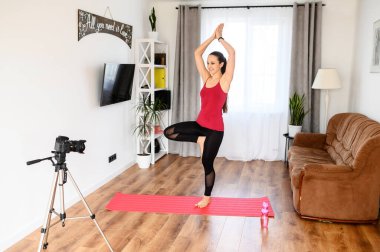 Genç bir kadın yoga videolarını evde kaydediyor.