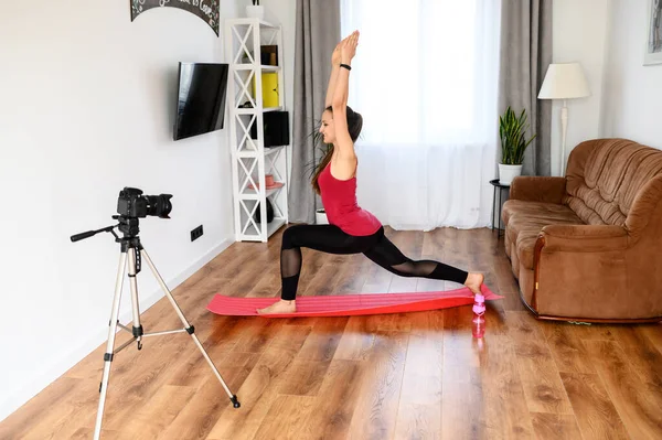 A young woman records yoga video tutorial at home