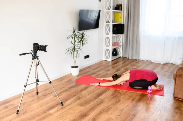 Genç bir kadın yoga videolarını evde kaydediyor.