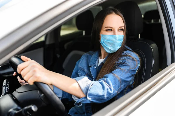 Junge Frau mit Schutzmaske fährt Auto — Stockfoto
