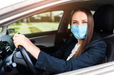 Young woman in protective mask is driving car clipart