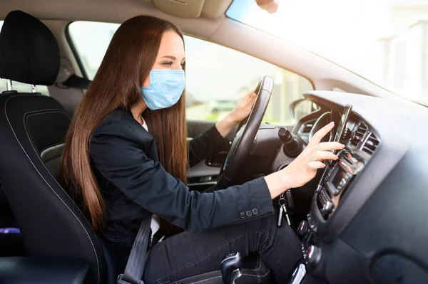 Молода жінка в захисній масці водить машину — стокове фото