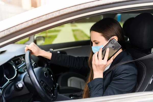 Young woman in protective mask is driving car