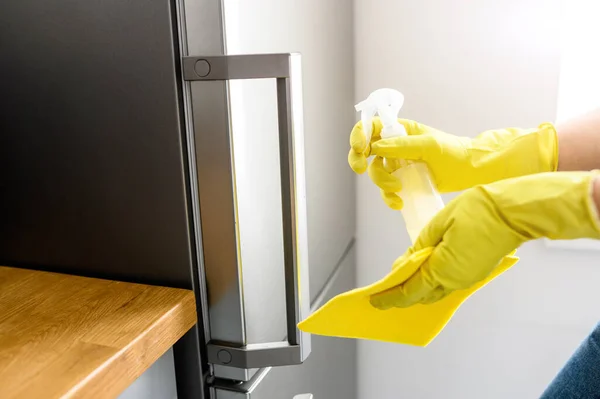 Hands in a gloves is cleaning the refrigerator