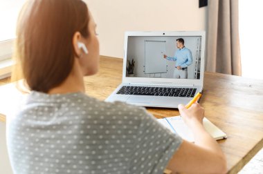 Evde online ders izleyen genç bir kadın.
