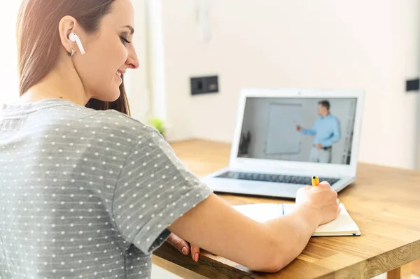 Uma jovem mulher assistindo aulas online em casa — Fotografia de Stock