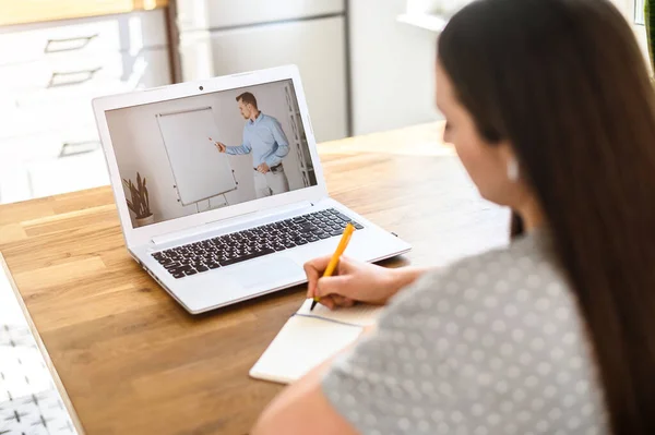 Uma jovem mulher assistindo aulas online em casa — Fotografia de Stock