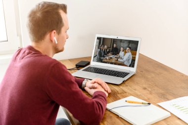 Genç bir adam video görüşmesi için dizüstü bilgisayar kullanıyor.