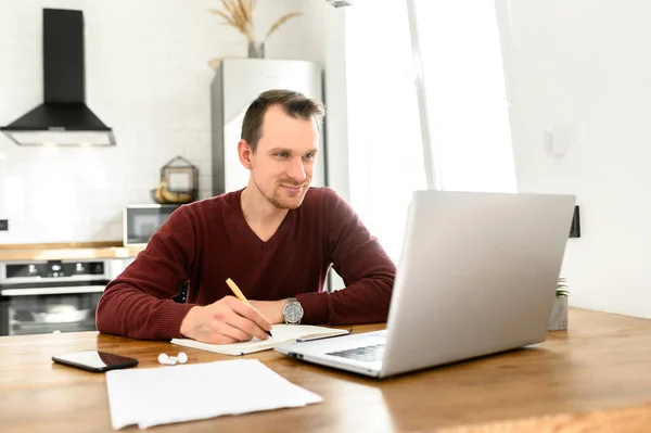 Un jeune homme étudie en ligne, regarde des webinaires — Photo