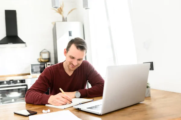 Een jonge man studeert online, kijkt naar webinars. — Stockfoto