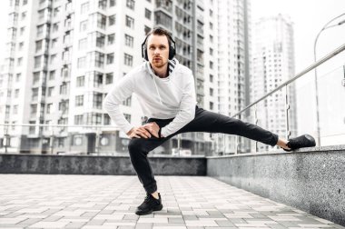 Spor kıyafetli genç adam dışarıda antrenman yapıyor.