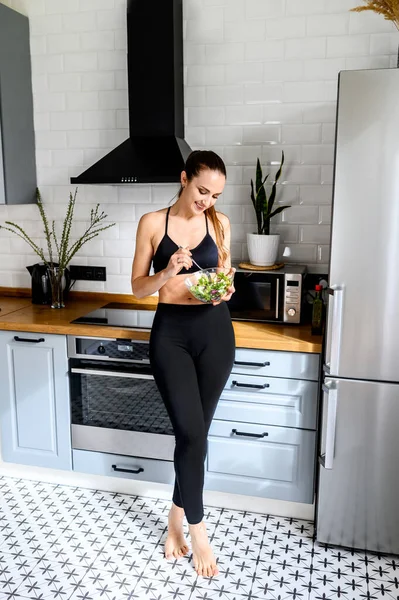 Giovane donna mangia salat in cucina — Foto Stock